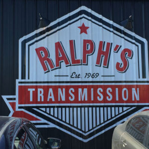 A pair of smooth, well-crafted cars, parked at the foot of the Ralph's Transmission logo.