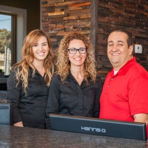 An image of three people standing behind the counter at Ralph's Transmission.