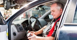 A man tests a car's computer with a machine.
