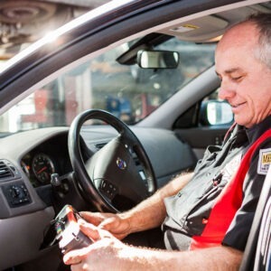 A man tests a car's computer with a machine.