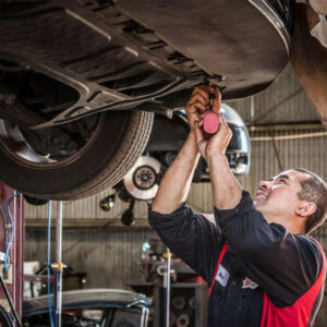 A man works with tools near the wheel of a car.