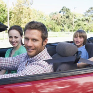 Four people relax in a red convertible.