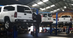 A series of vehicles lifted up on hydraulics for maintenance to be performed.