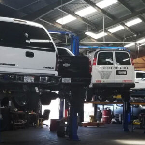 A series of vehicles lifted up on hydraulics for maintenance to be performed.