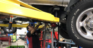 A technician explores the underbelly of a vehicle.