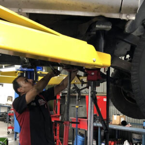 A technician explores the underbelly of a vehicle.