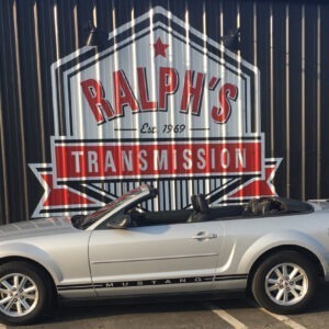 An early 2000s Mustang parked in front of the Ralph's Transmission logo