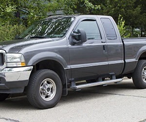 A grey truck on light grey pavement.