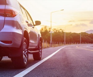 An image of a silver SUV on a sunny road.