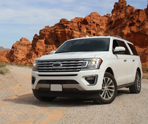 An image of a sharp looking Ford SUV with red, craggy desert mesas surrounding it.