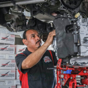 A man works on the components of a car with it raised over his head.