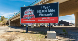 A Ralph's Transmission billboard that reads "3 year 100,000 mile warranty."