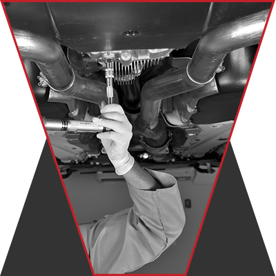 A man working on the underbelly of a car, taking something apart.