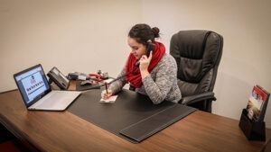 A woman works at a large desk on a phone.