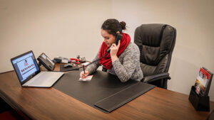 A woman works at a large desk on a phone.
