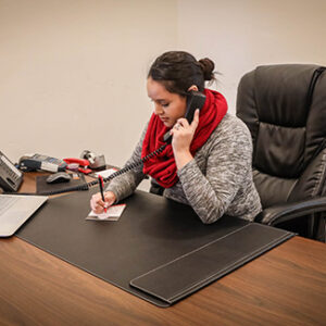 A woman works at a large desk on a phone.