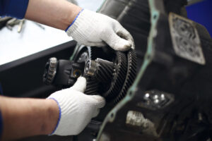 A man with soft, white gloves adjusts components in a vehicle.