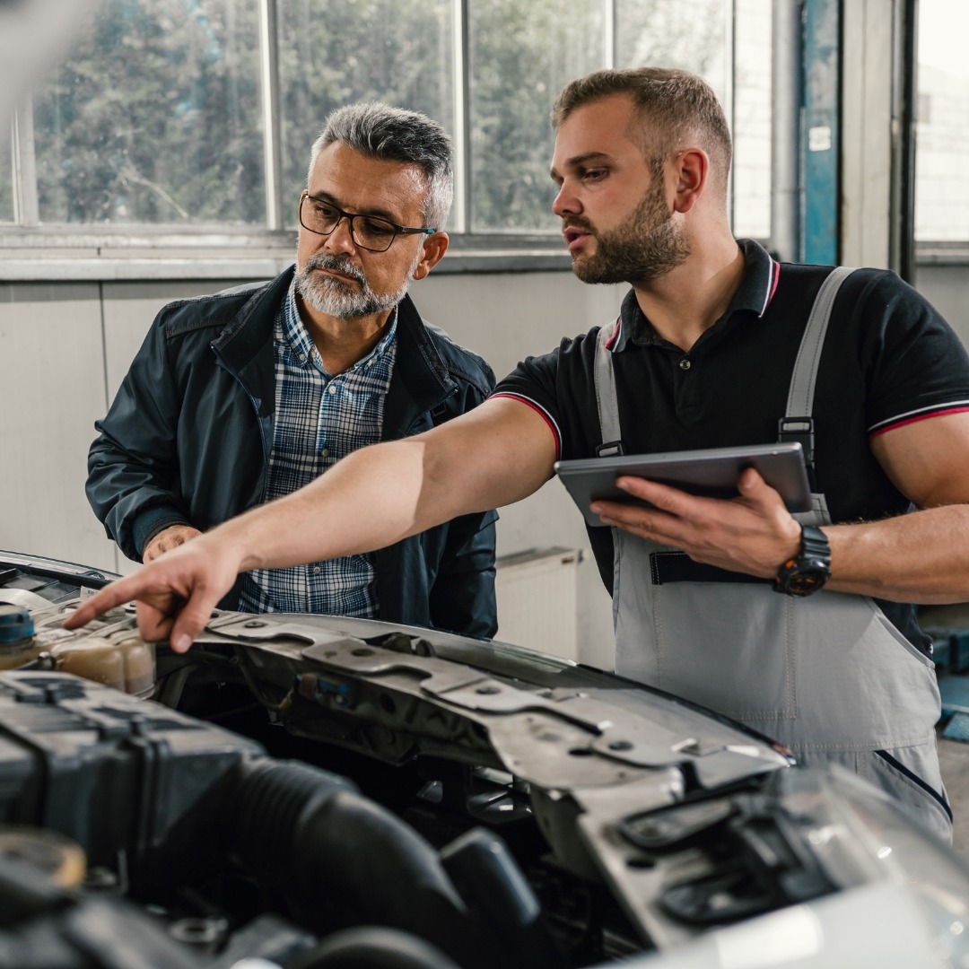A mechanic looking at a customer's engine with them