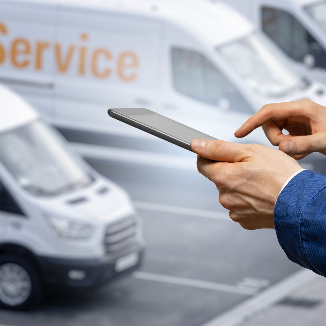 Clicking on tablet in front of a fleet of vans